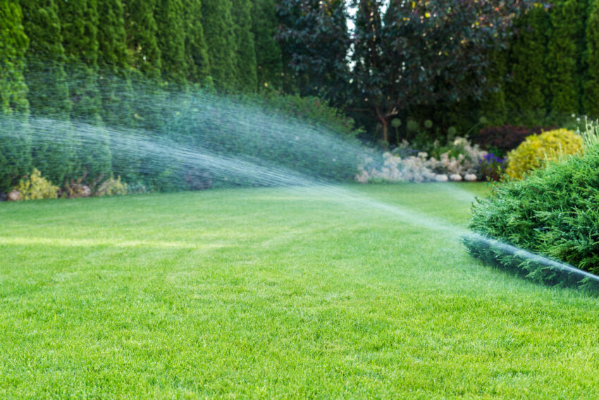 Automatic sprinkler system watering a green lawn